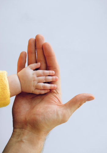 tiny baby hand on top of adult's palm