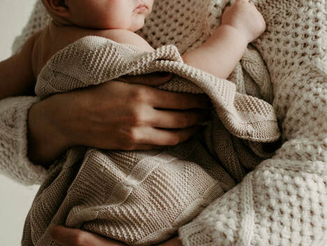 woman holding baby wrapping in a sweater